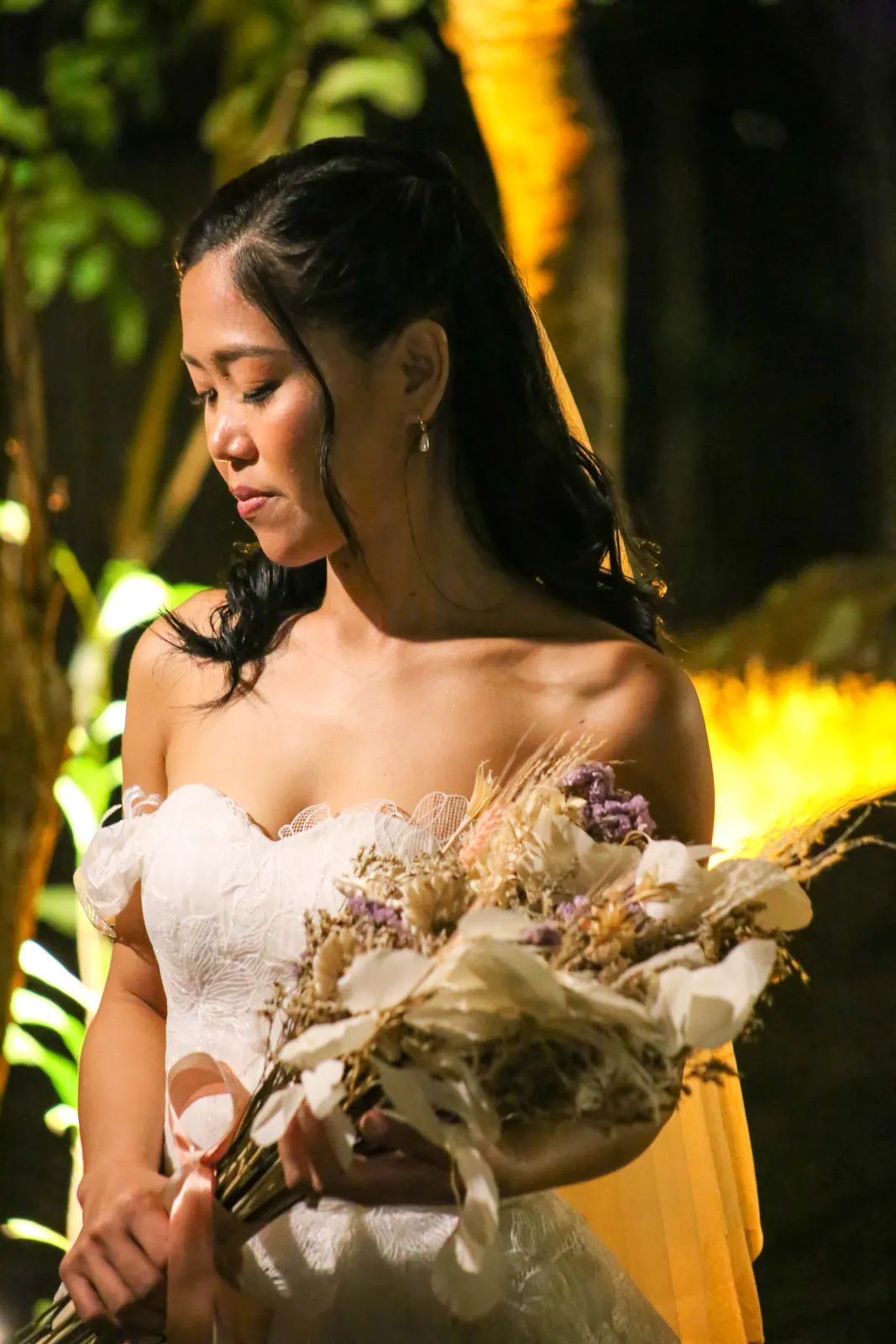 La mariée et son bouquet de fleurs séchées sous les arbres