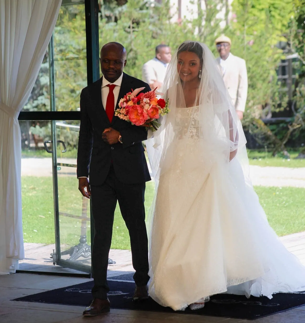 La mariée avance, bouquet rouge à la main