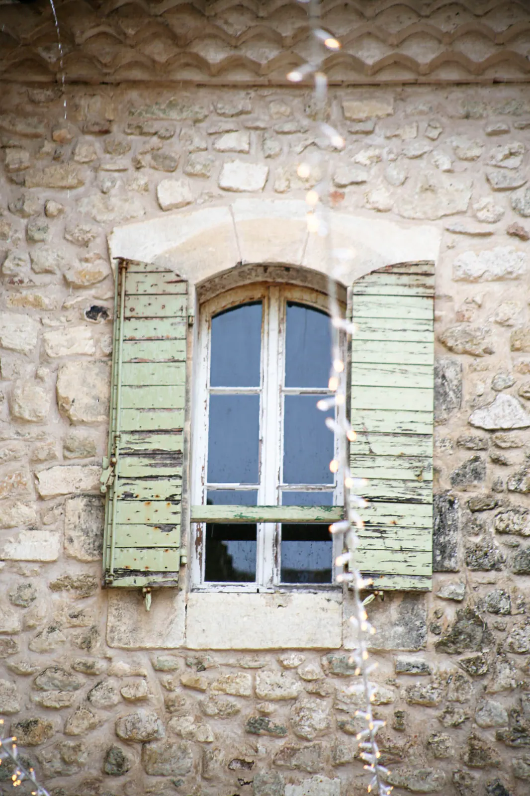 Fenêtre aux volets verts sur la façade en pierre